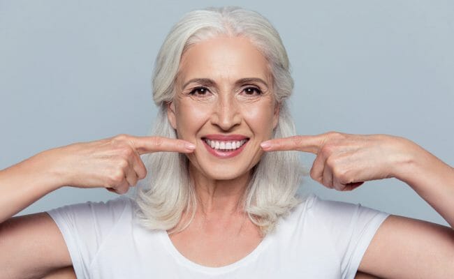 older woman pointing at her smile